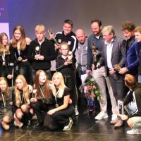 De winnaars van 2023 samen op het podium.